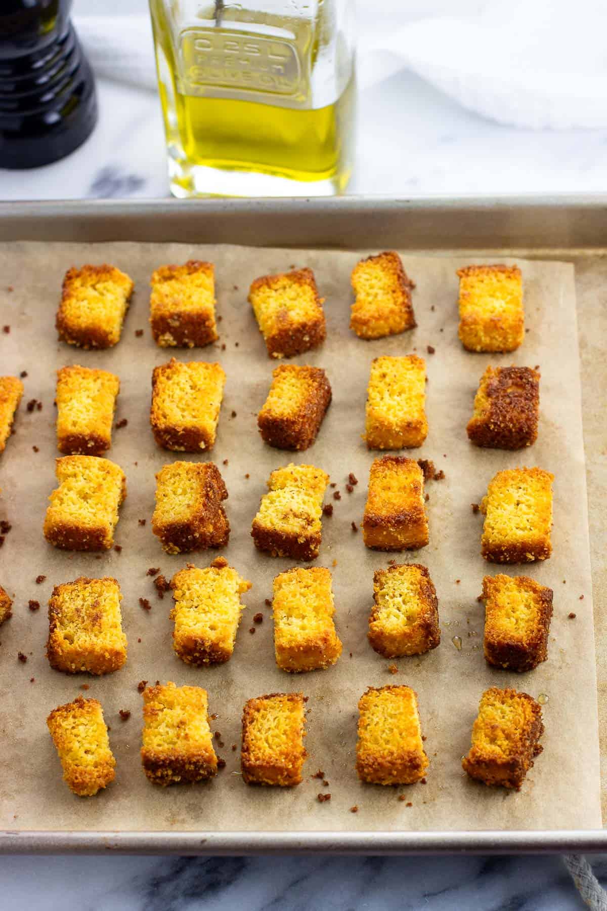 Crispy baked cornbread croutons on a pan.