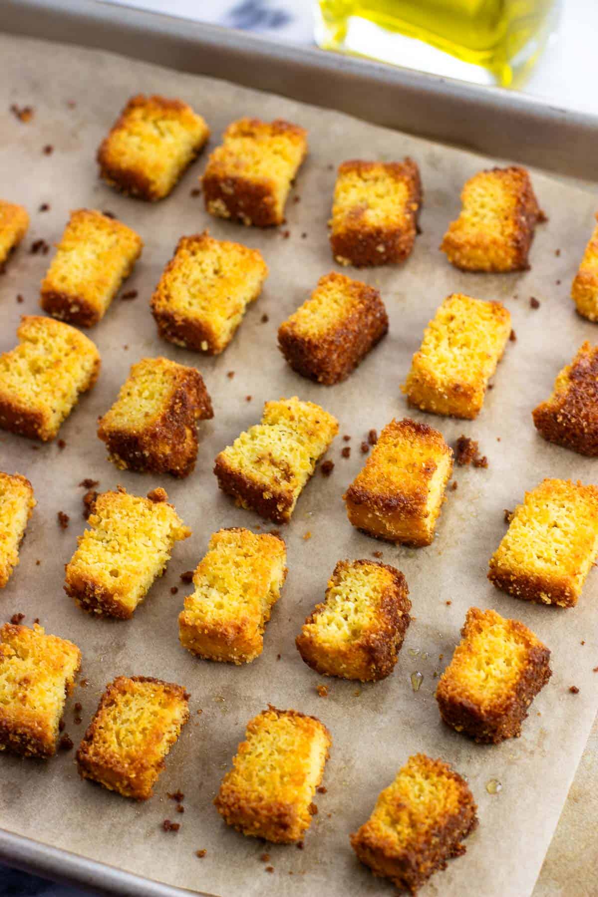 Baked cornbread croutons on a sheet pan.