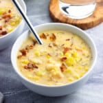 A bowl of corn and shrimp chowder topped with crumbled bacon.