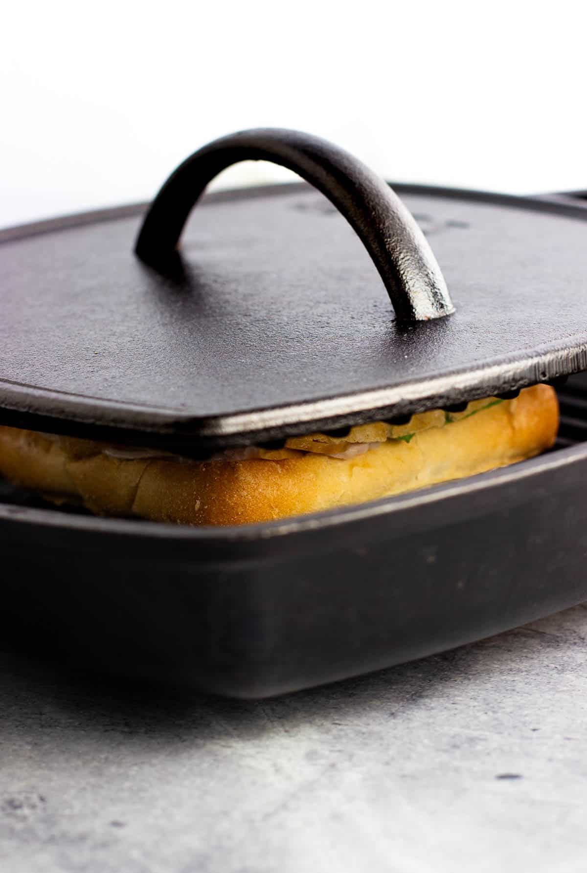 A panini being cooked in a cast iron panini press.