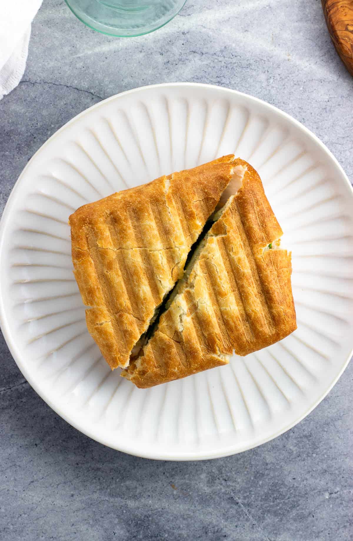 A square ciabatta panini cut in half on a plate.