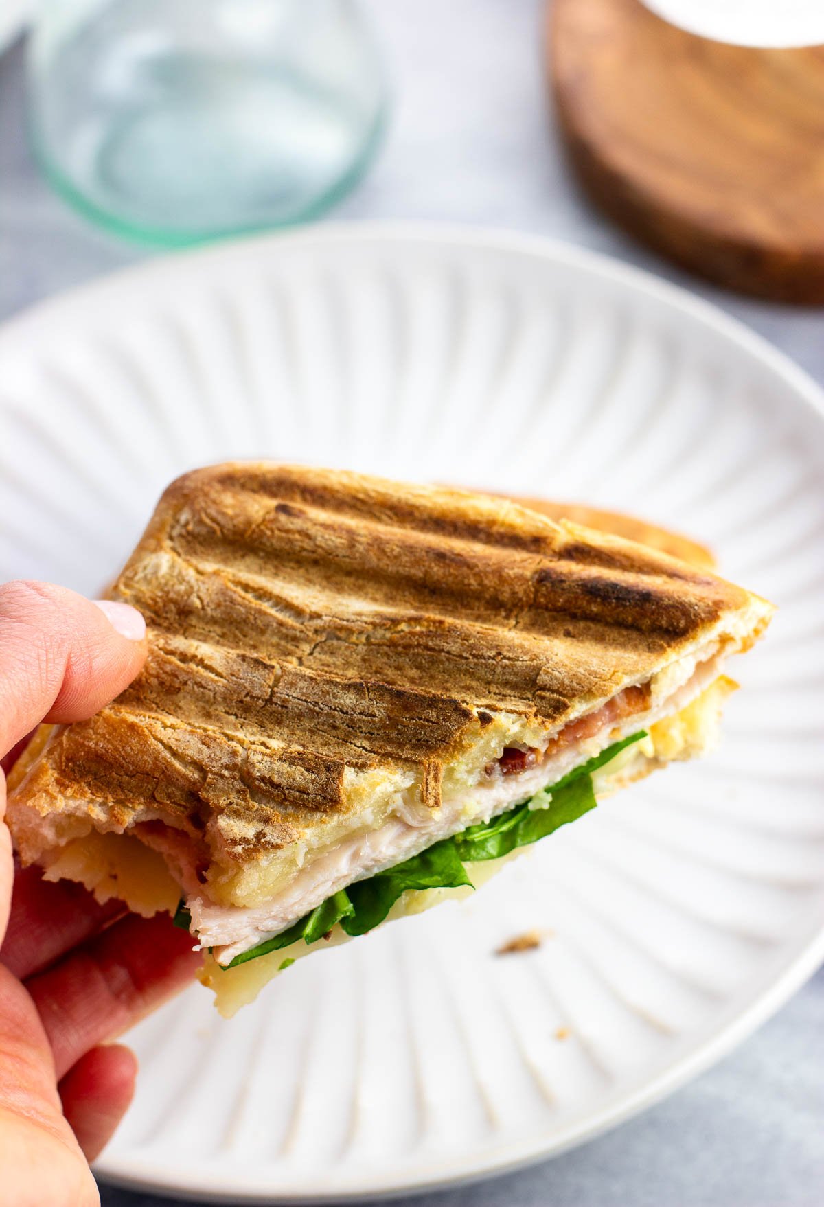 A hand holding up a panini showing the crisp grilled bread.