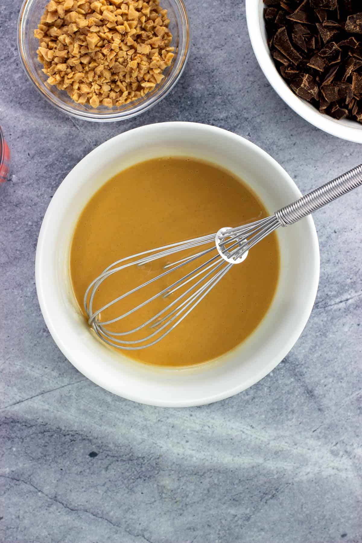 Melted peanut butter shell in a bowl with a whisk.
