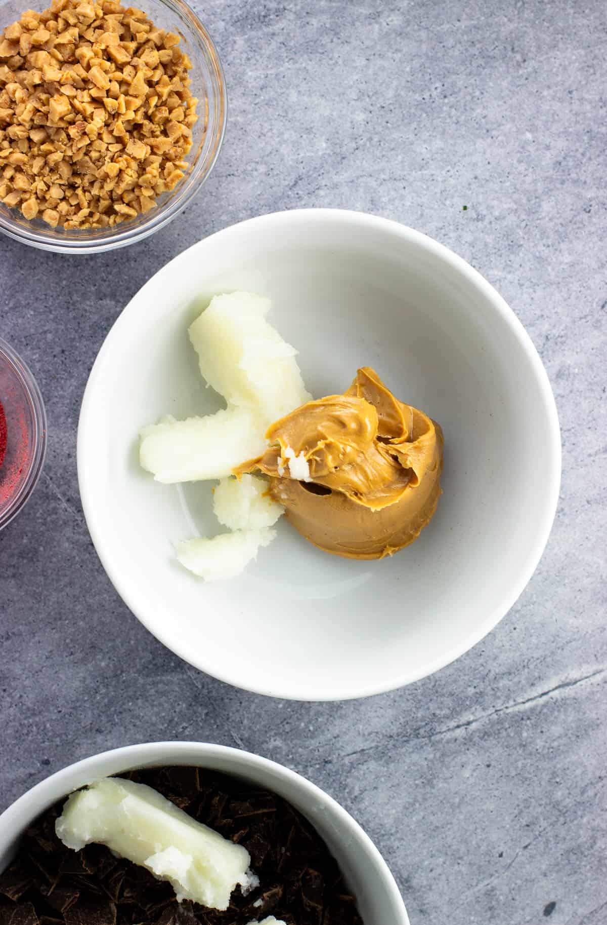 Creamy peanut butter and coconut oil in a bowl before melting.