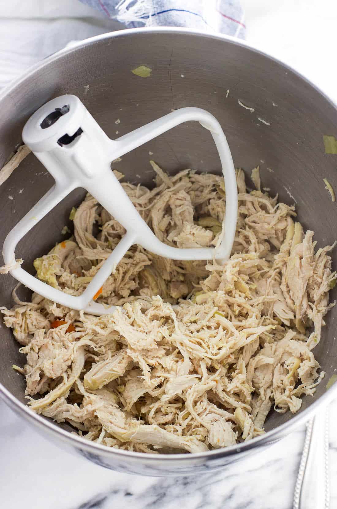 Cooked shredded chicken in a stand mixer bowl.