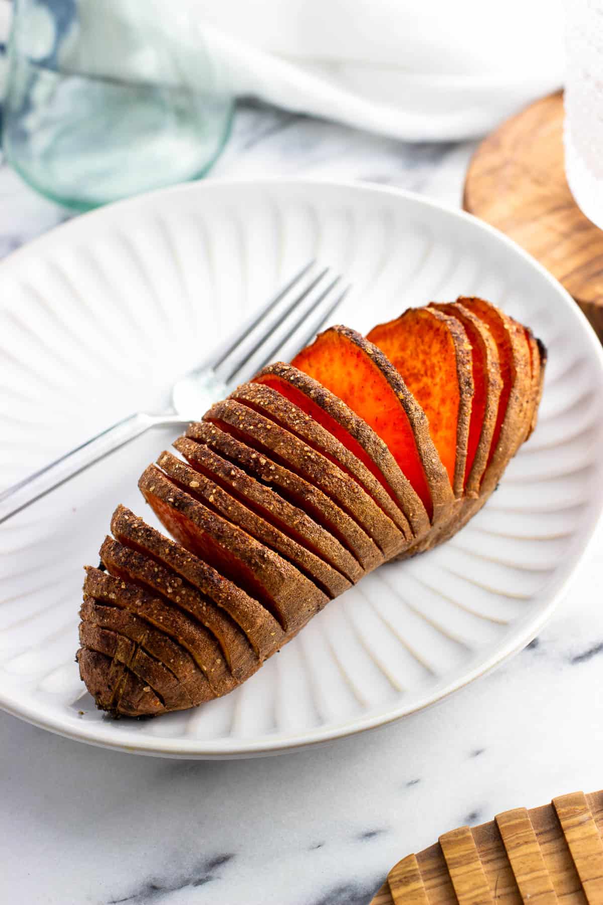 A hasselback-style sweet potato on a plate.
