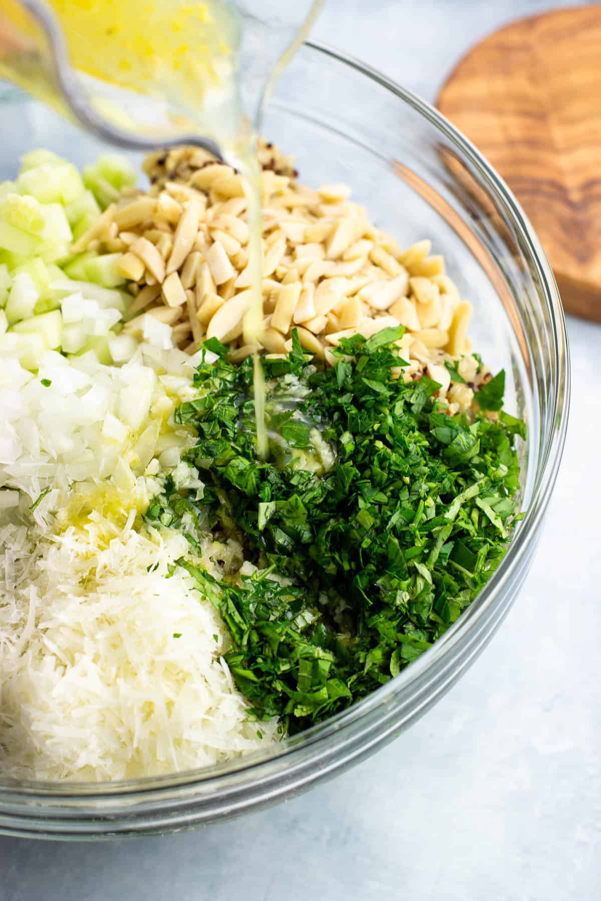 The lemon olive oil dressing being poured over the salad before tossing.