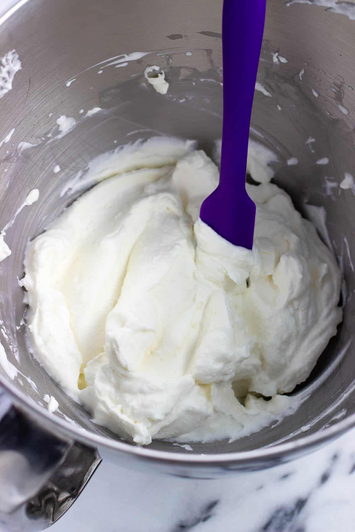 Fluffy gelatin-stabilized whipped cream in a bowl with a spatula.