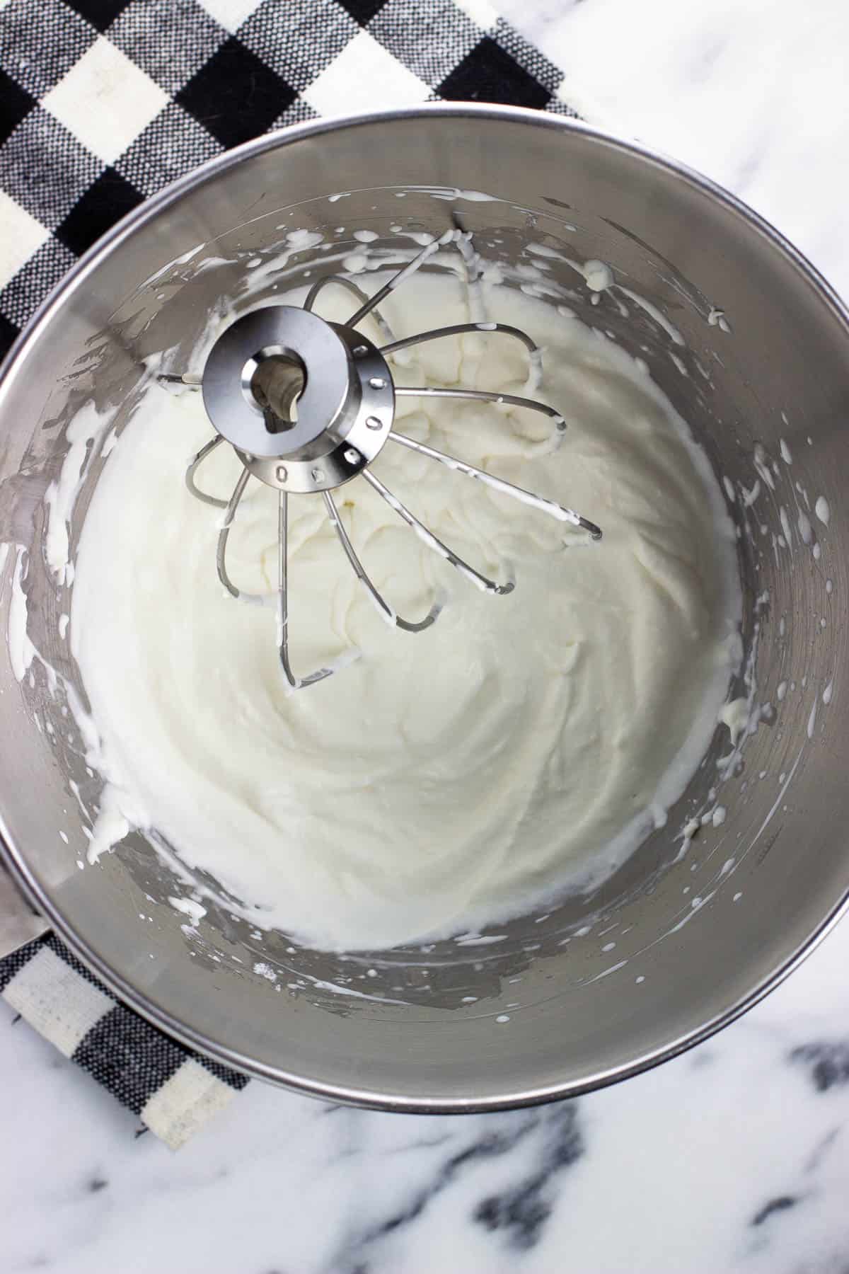 Whipped cream in-process in a stand mixer bowl with the whisk attachment.