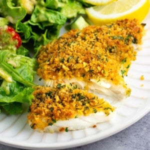 A baked cod fillet cut in half to show the flaky opaque fish.