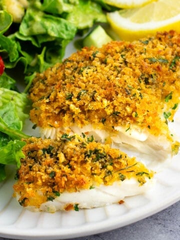 A baked cod fillet cut in half to show the flaky opaque fish.