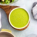 A small ceramic bowl of pesto salad dressing.