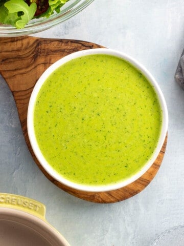 A small ceramic bowl of pesto salad dressing.