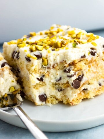 A forkful of cake laying next to a piece on a plate.