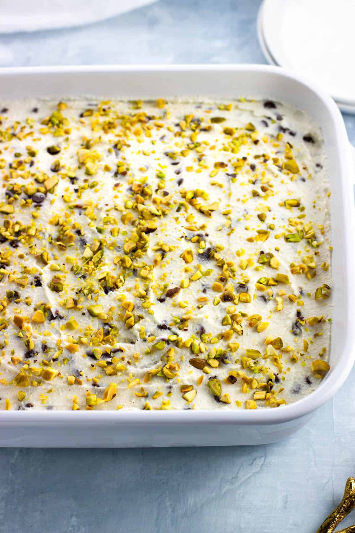 Cannoli icebox cake in a rectangular pan sprinkled with chopped pistachios.