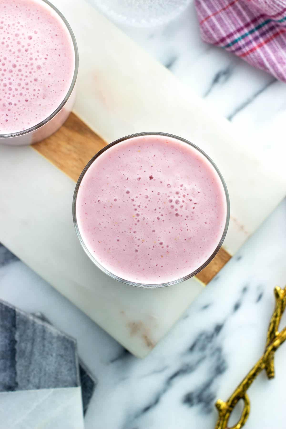 An overhead view of strawberry pineapple cottage cheese smoothies in glasses.