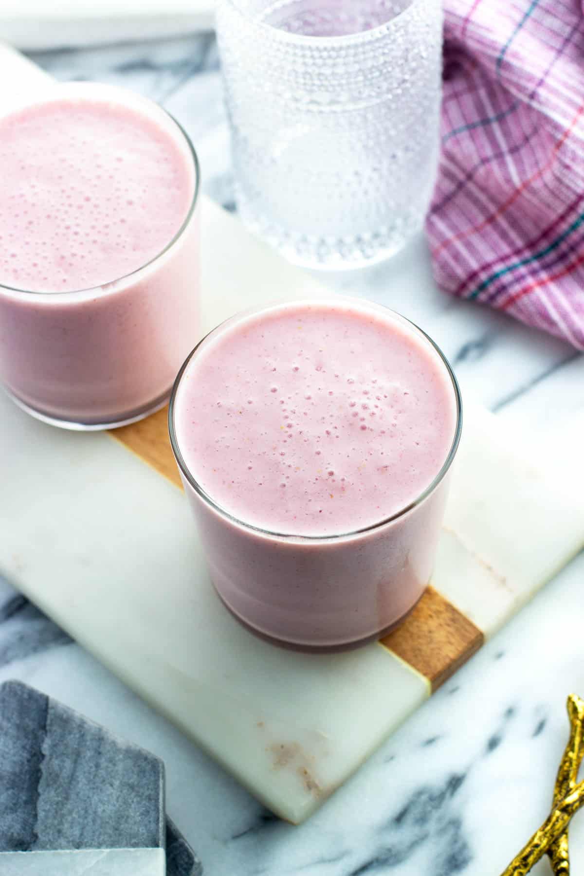 Two cottage cheese smoothies in short glasses on a stone serving tray.