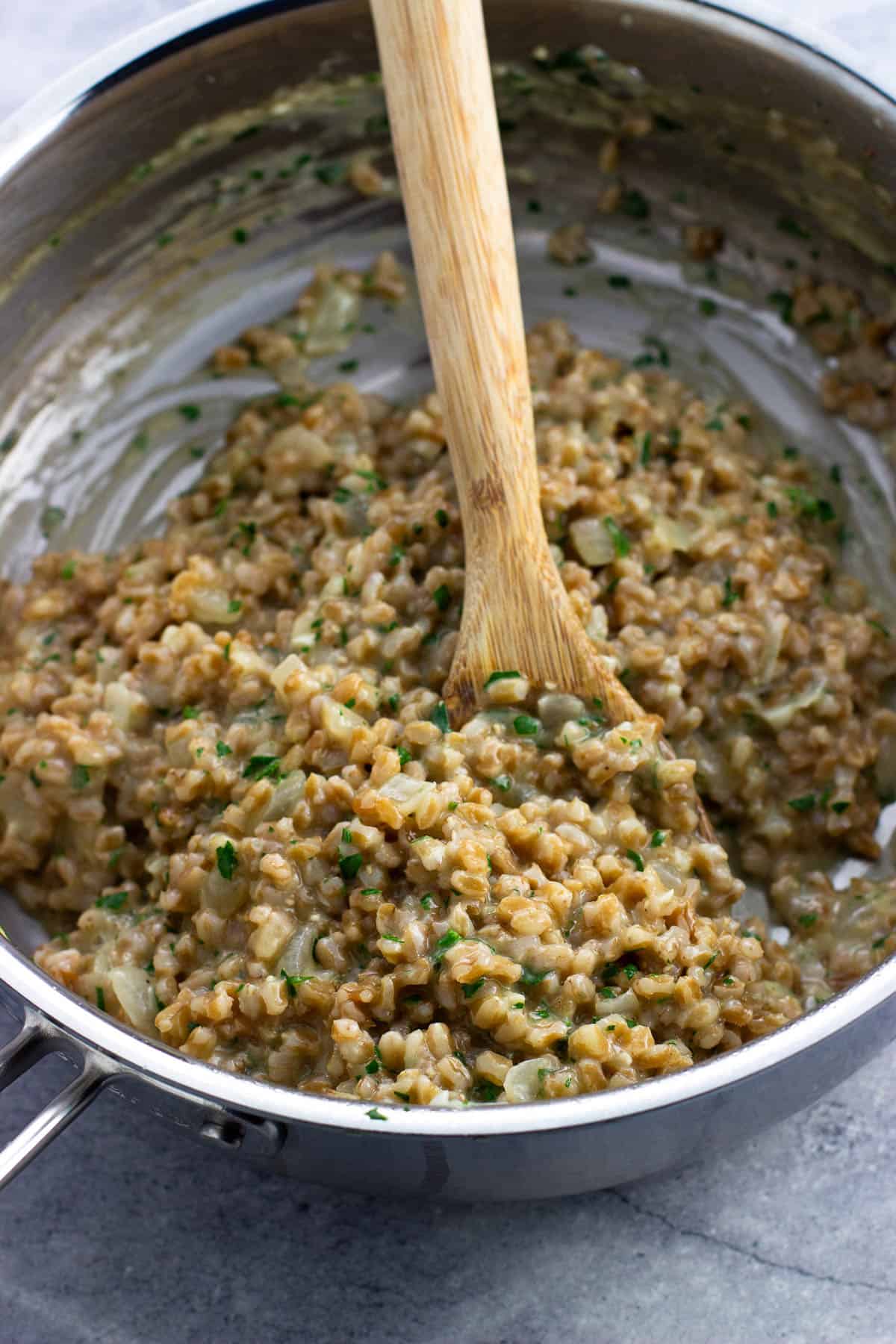 Farrotto in the saucepan with a wooden serving spoon.