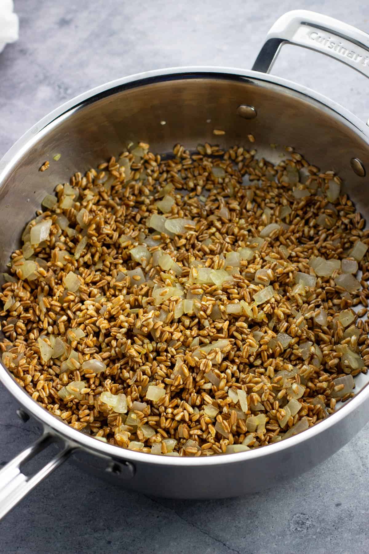 Farro added to the pan to toast.