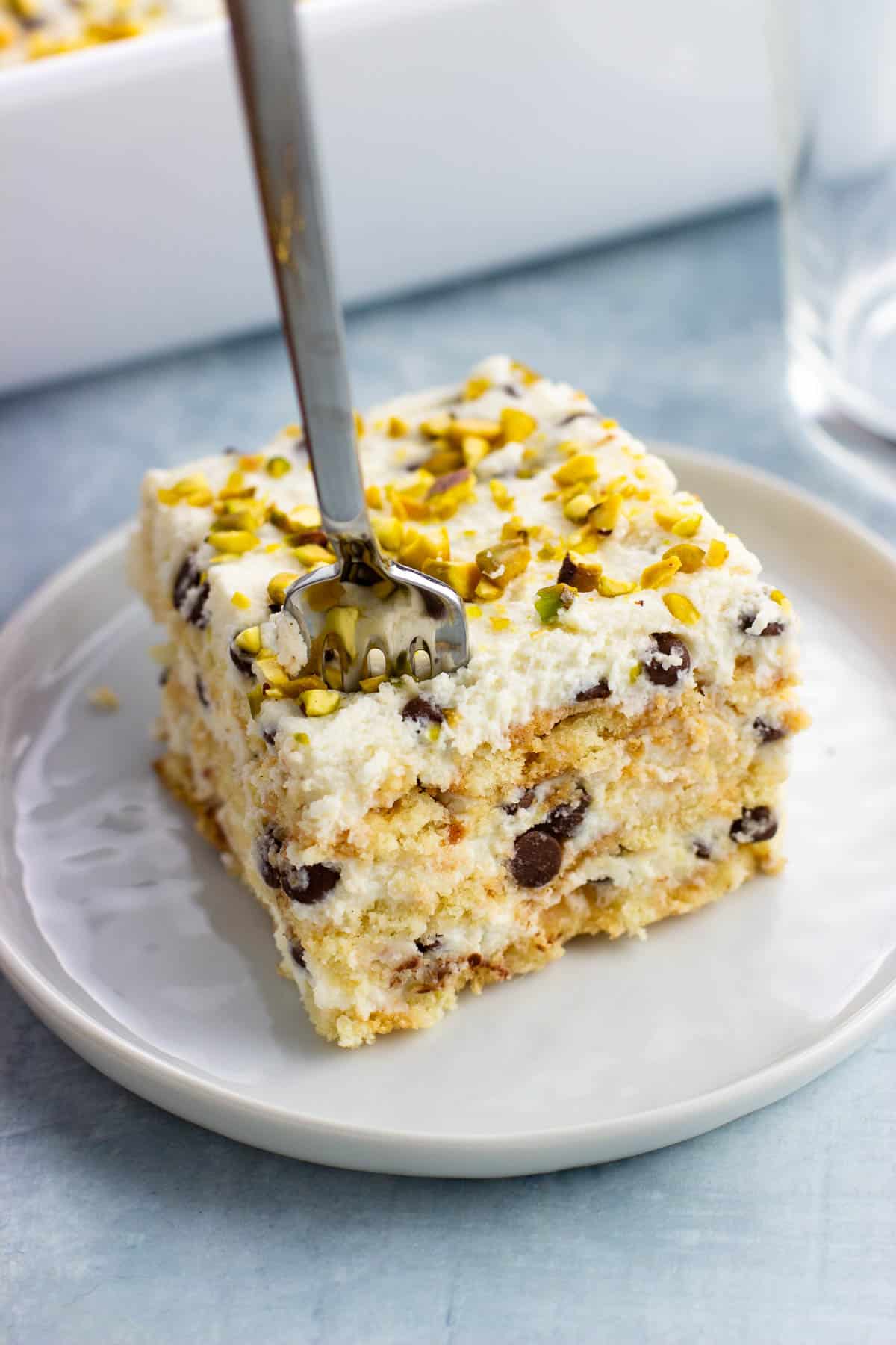 A fork being plunged into a piece of cake on a plate.