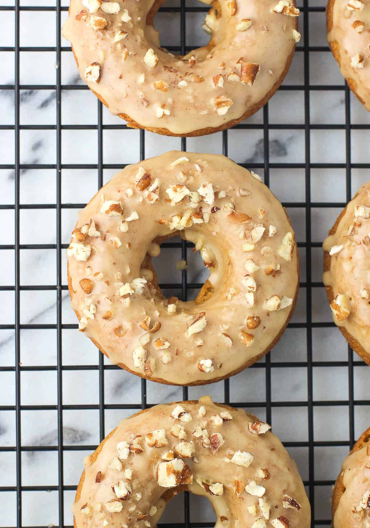 Glazed pumpkin donuts topped with chopped pecans.