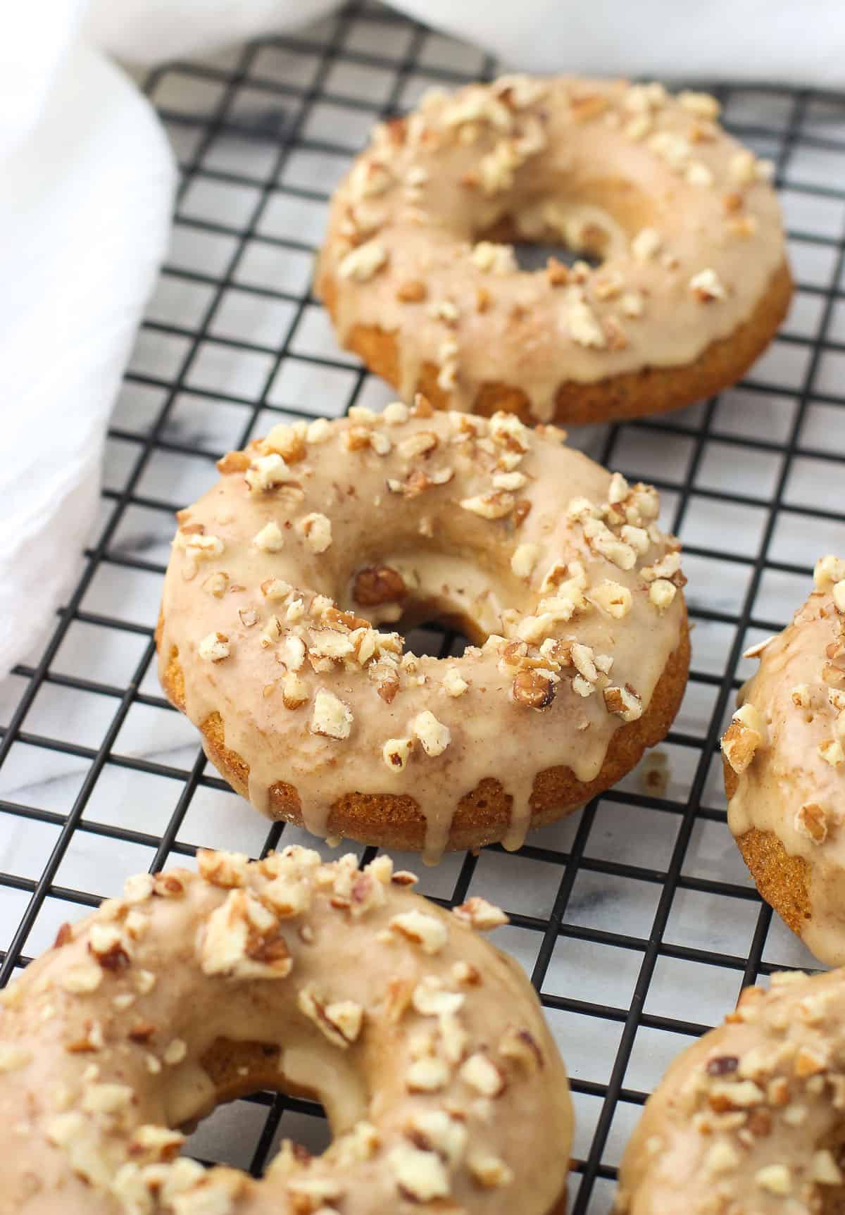 Glazed pumpkin donuts topped with chopped pecans.