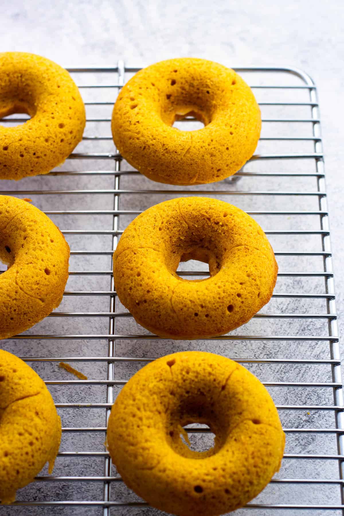 Baked pumpkin donuts cooling on a wire rack.