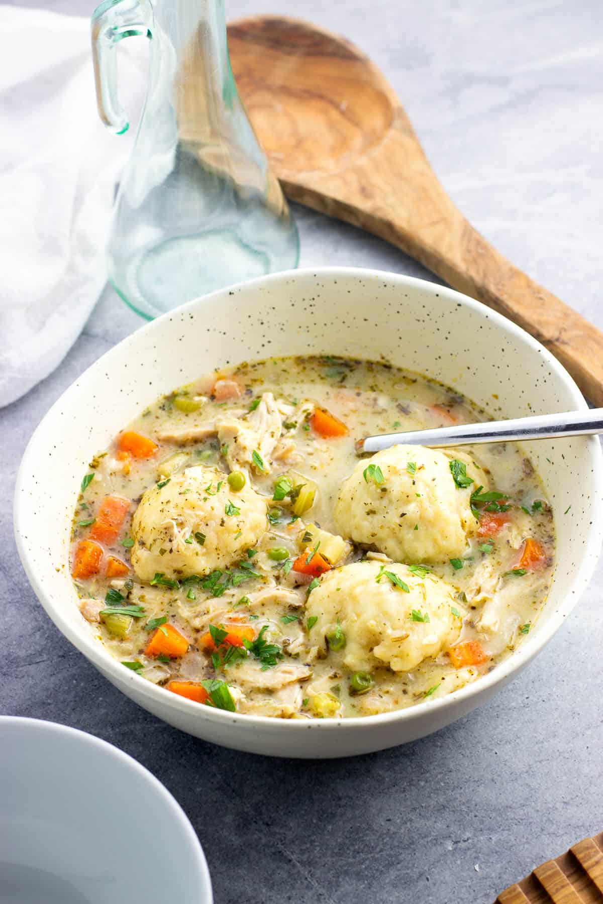 A bowl of chicken and dumplings garnished with fresh parsley.
