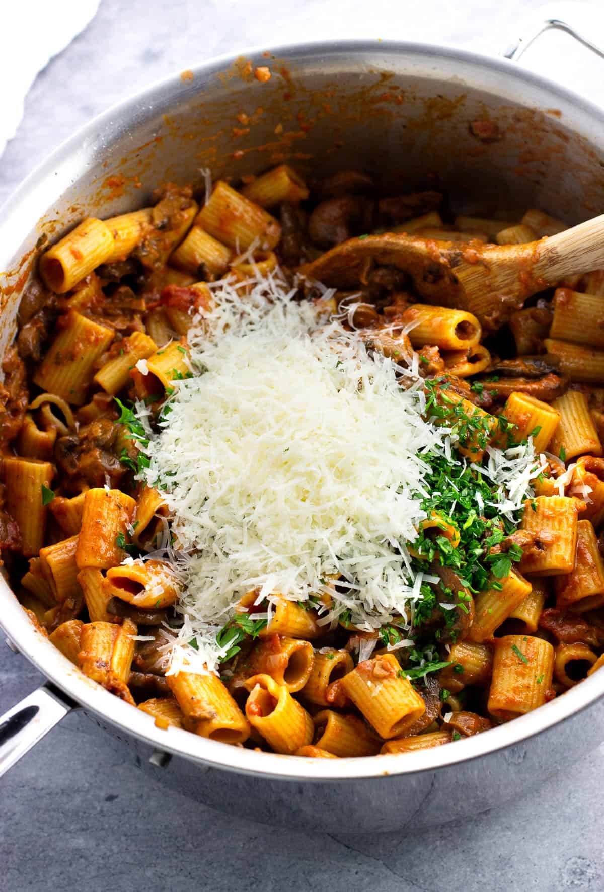 Cheese and parsley being added to the pot of pasta.