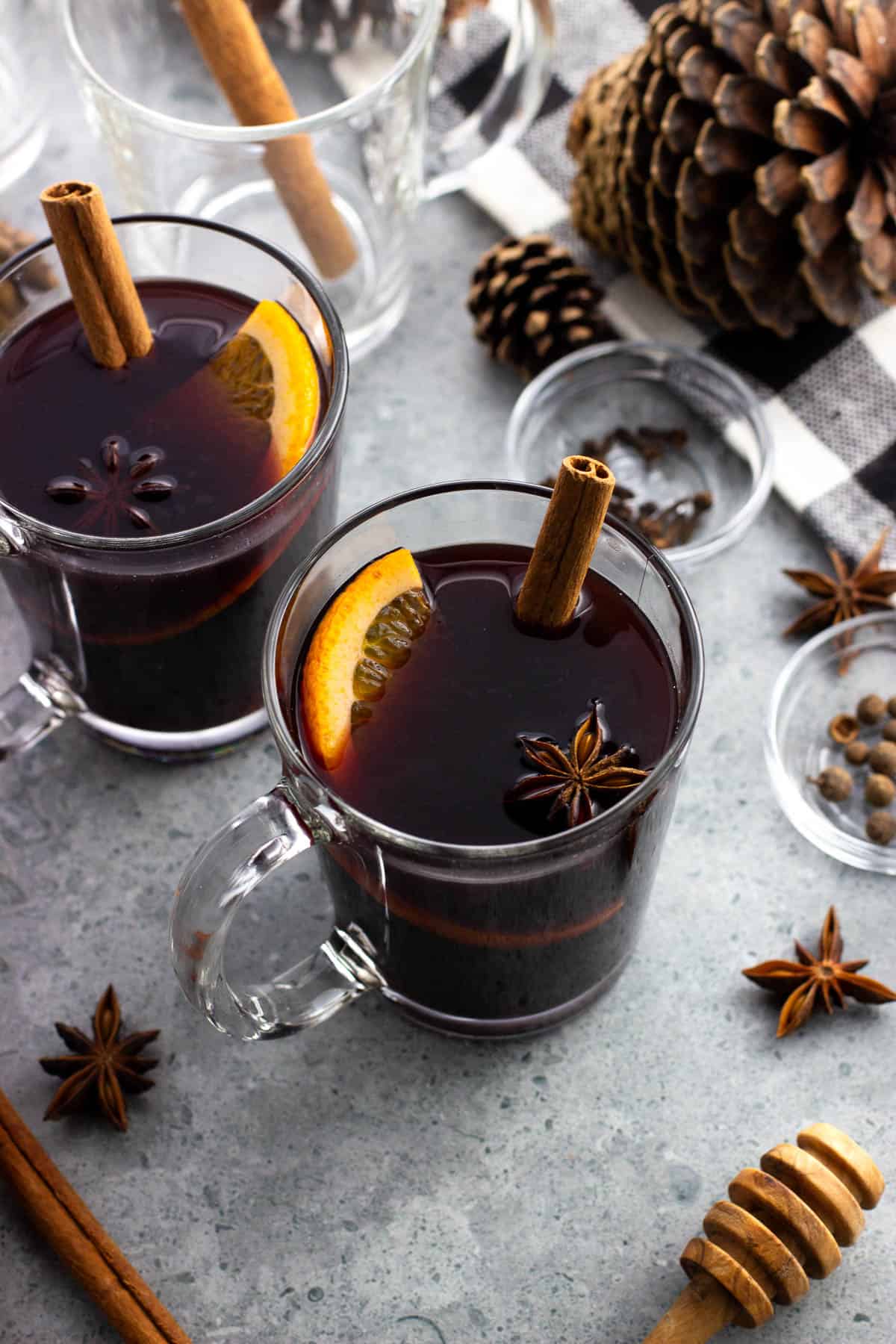 Mugs of Italian mulled wine garnished with cinnamon sticks, orange slices, and star anise pods.