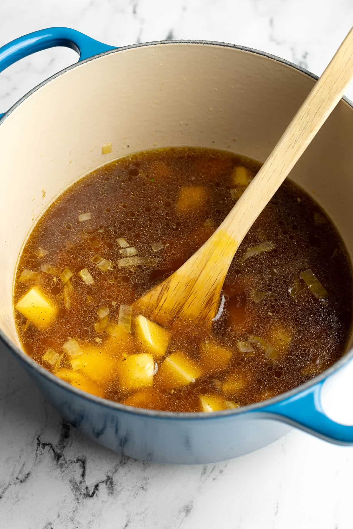 Broth and potatoes added to the soup pot.