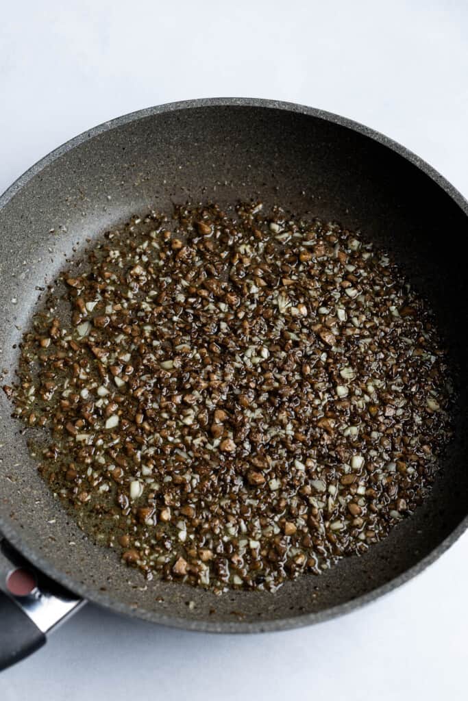 Mushroom stems and garlic sautéed in a pan of olive oil.