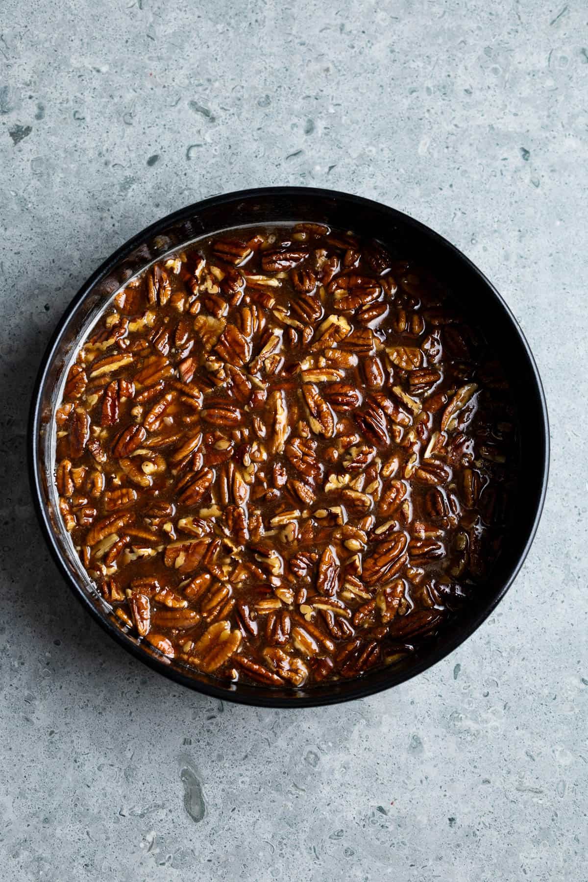 The pecan topping poured into the round cake pan.