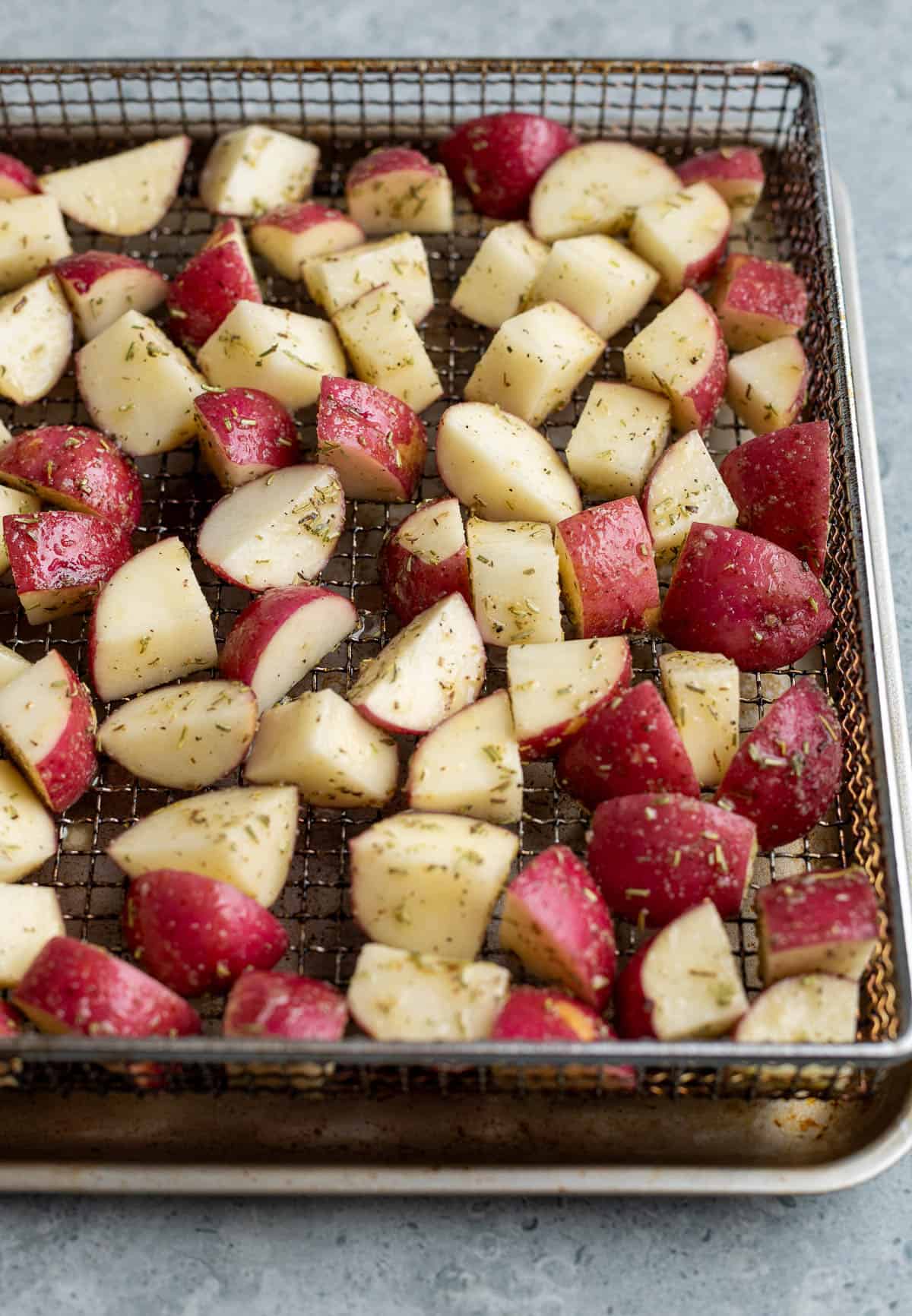 Red potato chunks on the air fryer basket before cooking.