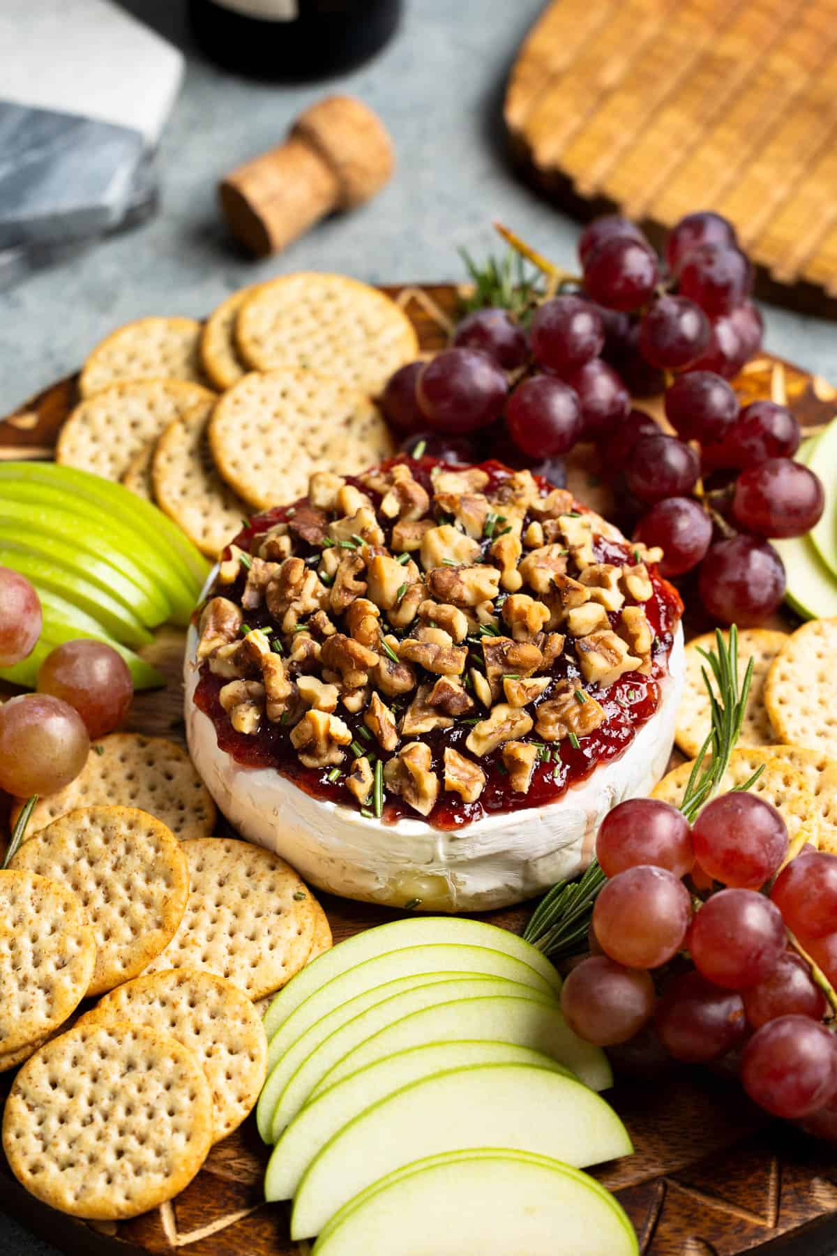 Baked brie topped with jam and walnuts served with apple slices, grapes, and crackers.