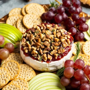 Baked brie topped with jam and walnuts served with apple slices, grapes, and crackers.