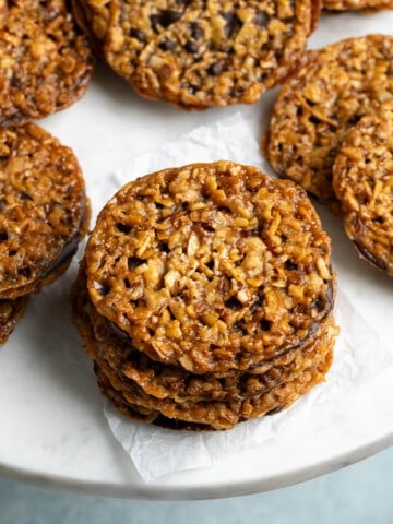 Florentine cookies pressed together with chocolate on a serving board.