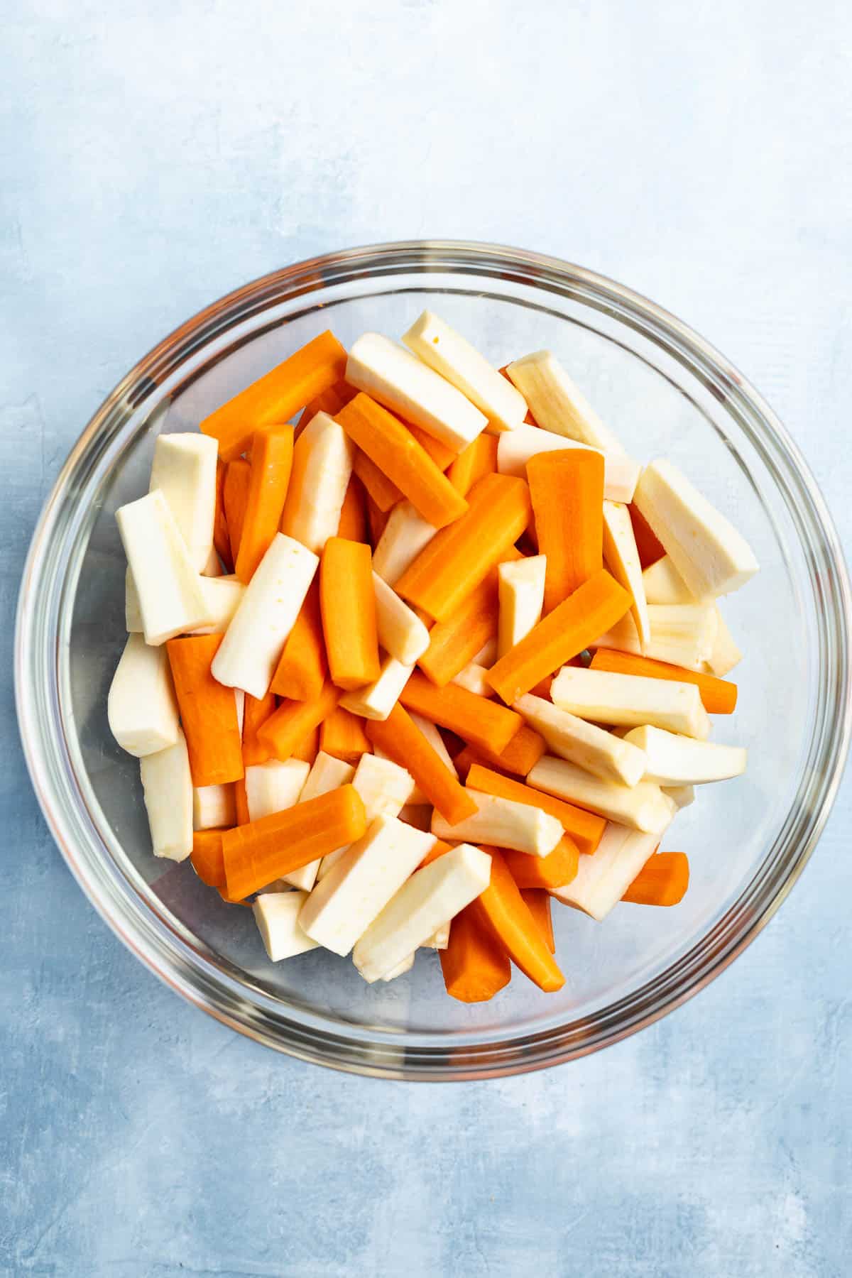 Sliced raw carrots and parsnips in a bowl.