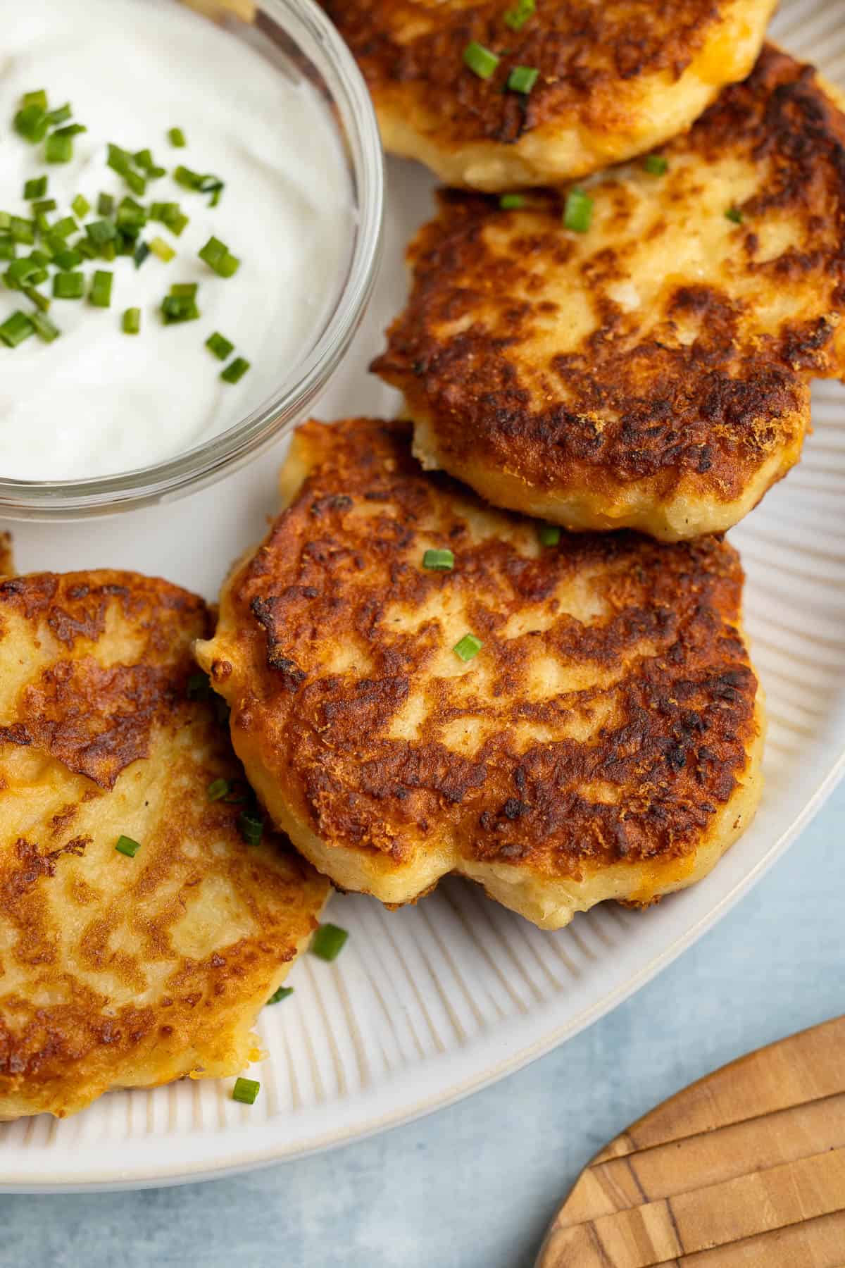 Pan-fried potato cakes on a plate with sour cream.