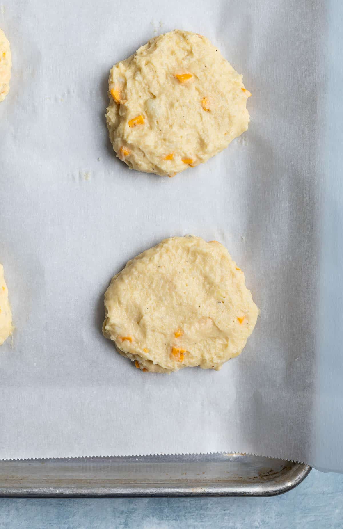 Shaped mashed potato patties on a parchment-lined pan.