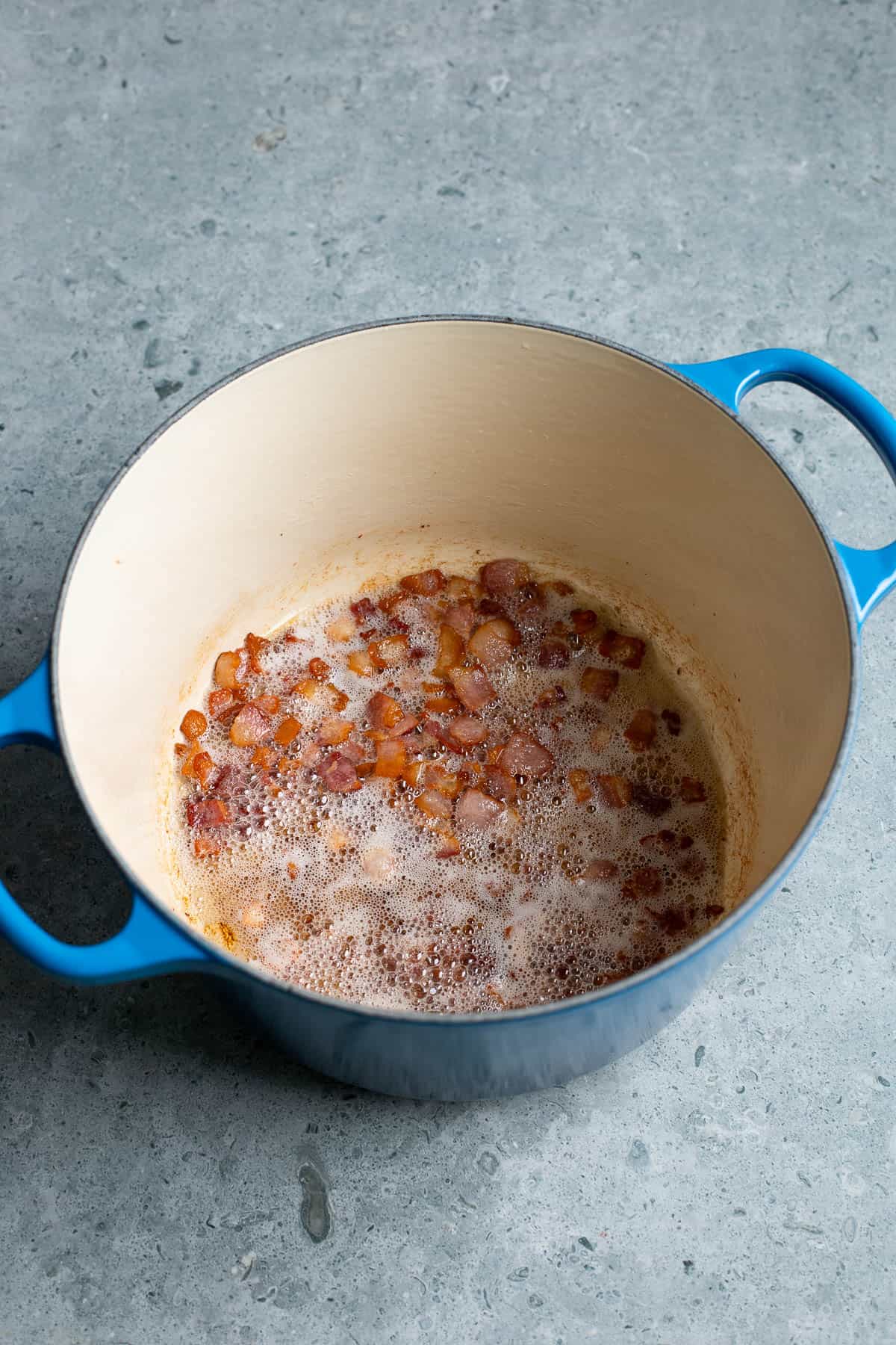 Diced bacon cooking in a pot.