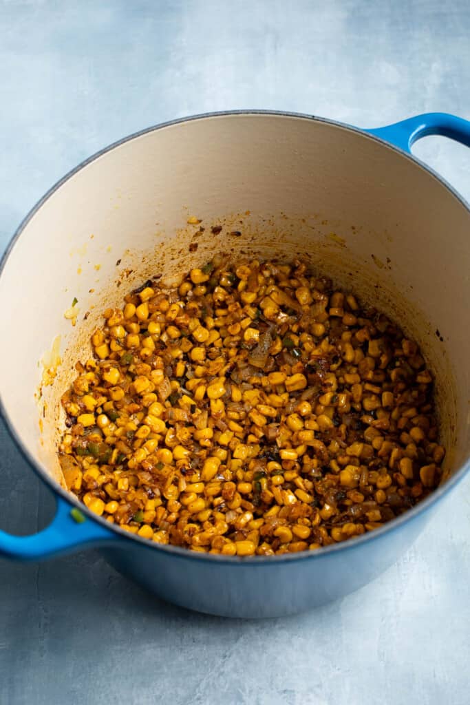 Seasoned roasted corn and vegetables in a large pot.