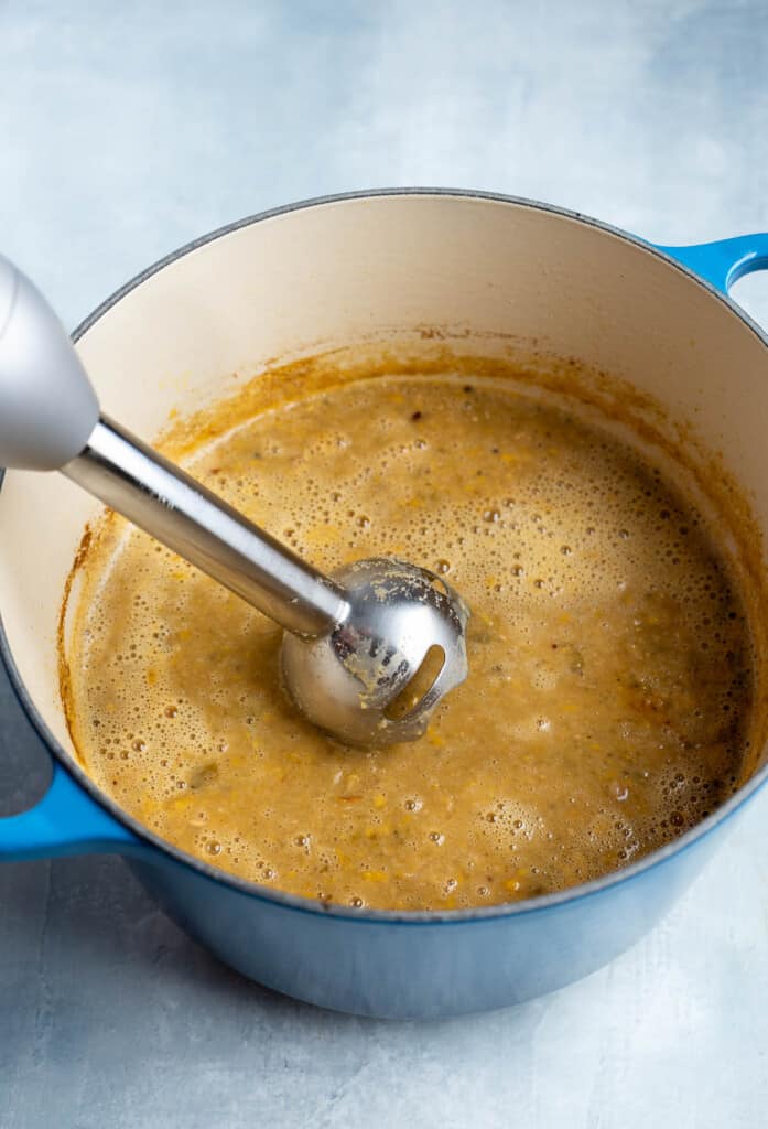 An immersion blender pureeing the chili.