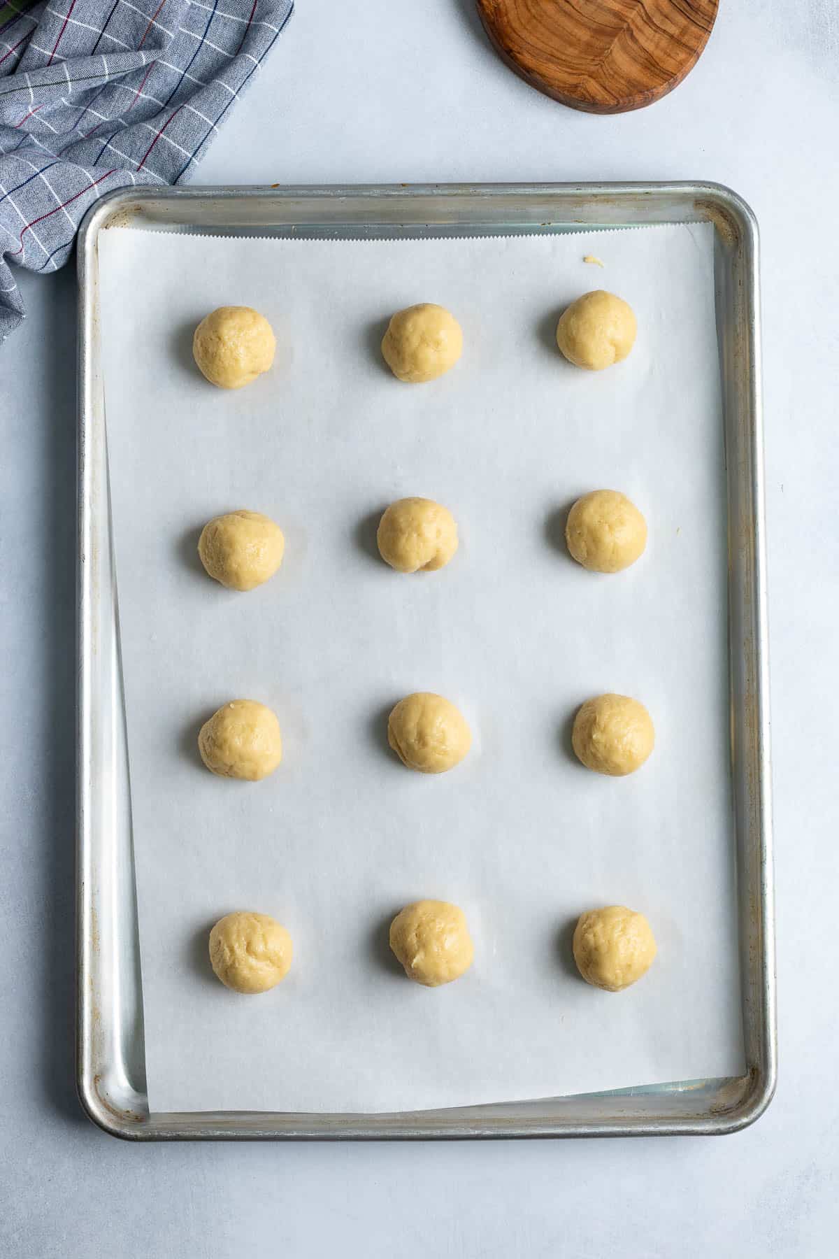 Scooped anise cookie dough on a parchment-lined baking sheet.