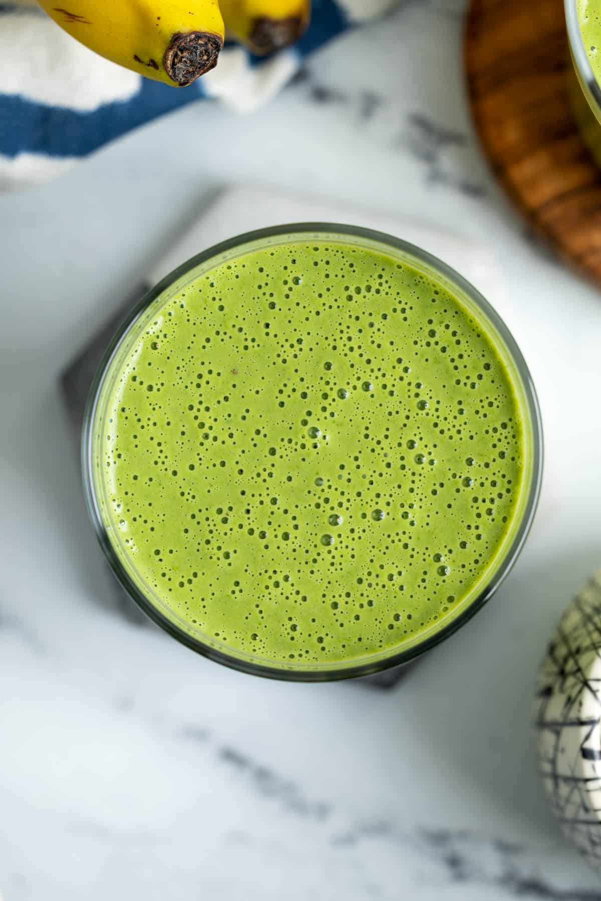 A well-blended collard greens smoothie in a glass with lots of bubbles.