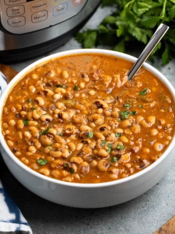 A serving bowl of seasoned black eyed peas in front of an Instant Pot.