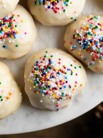 Italian anise cookies on a round marble serving board.