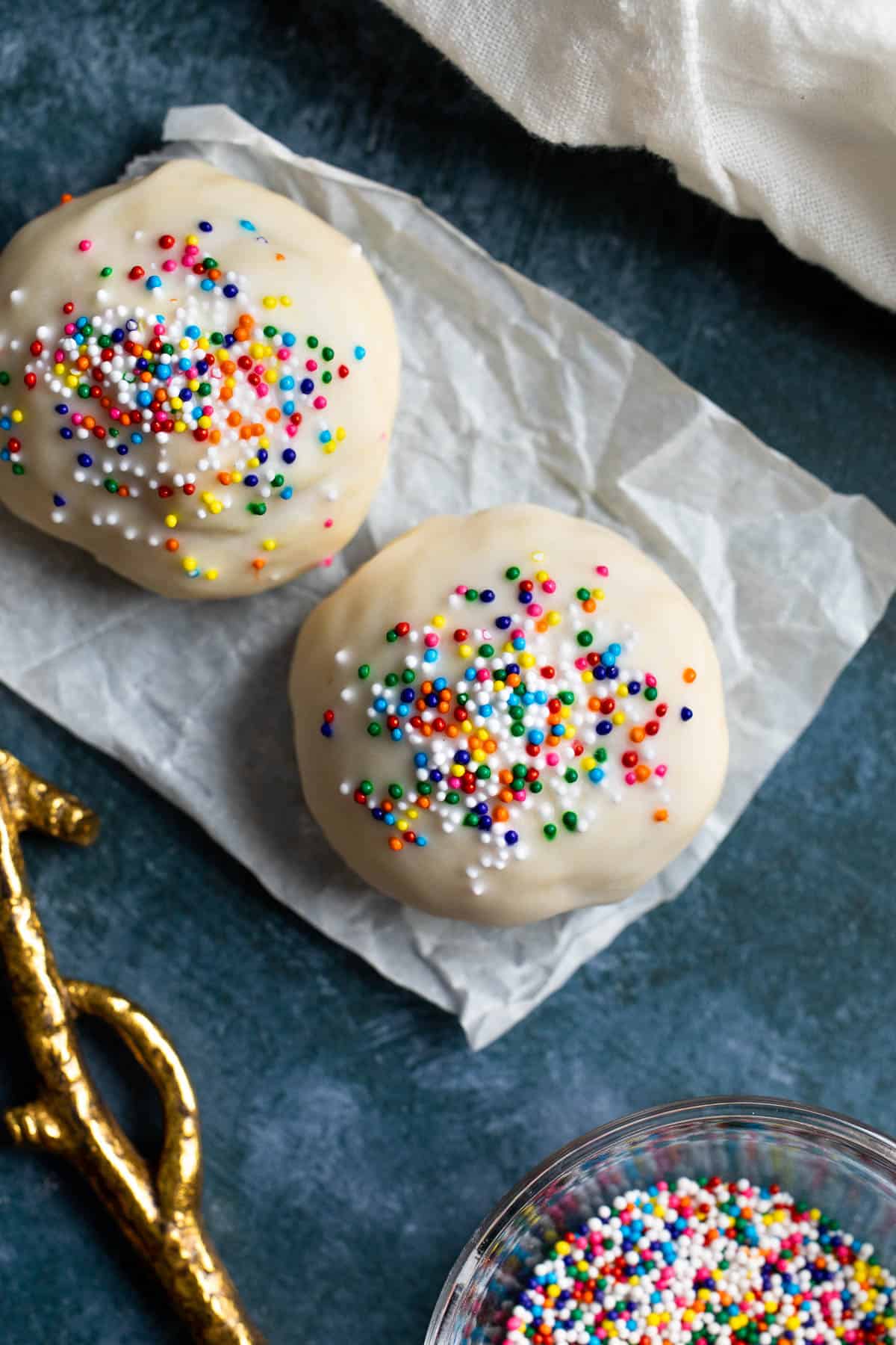 Two homemade anise cookies on a sheet of crinkled parchment paper.