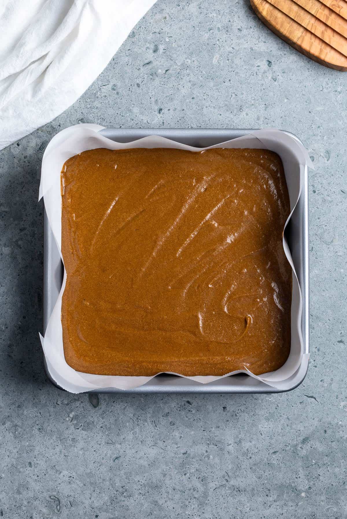 Batter poured into a parchment-lined square baking dish.