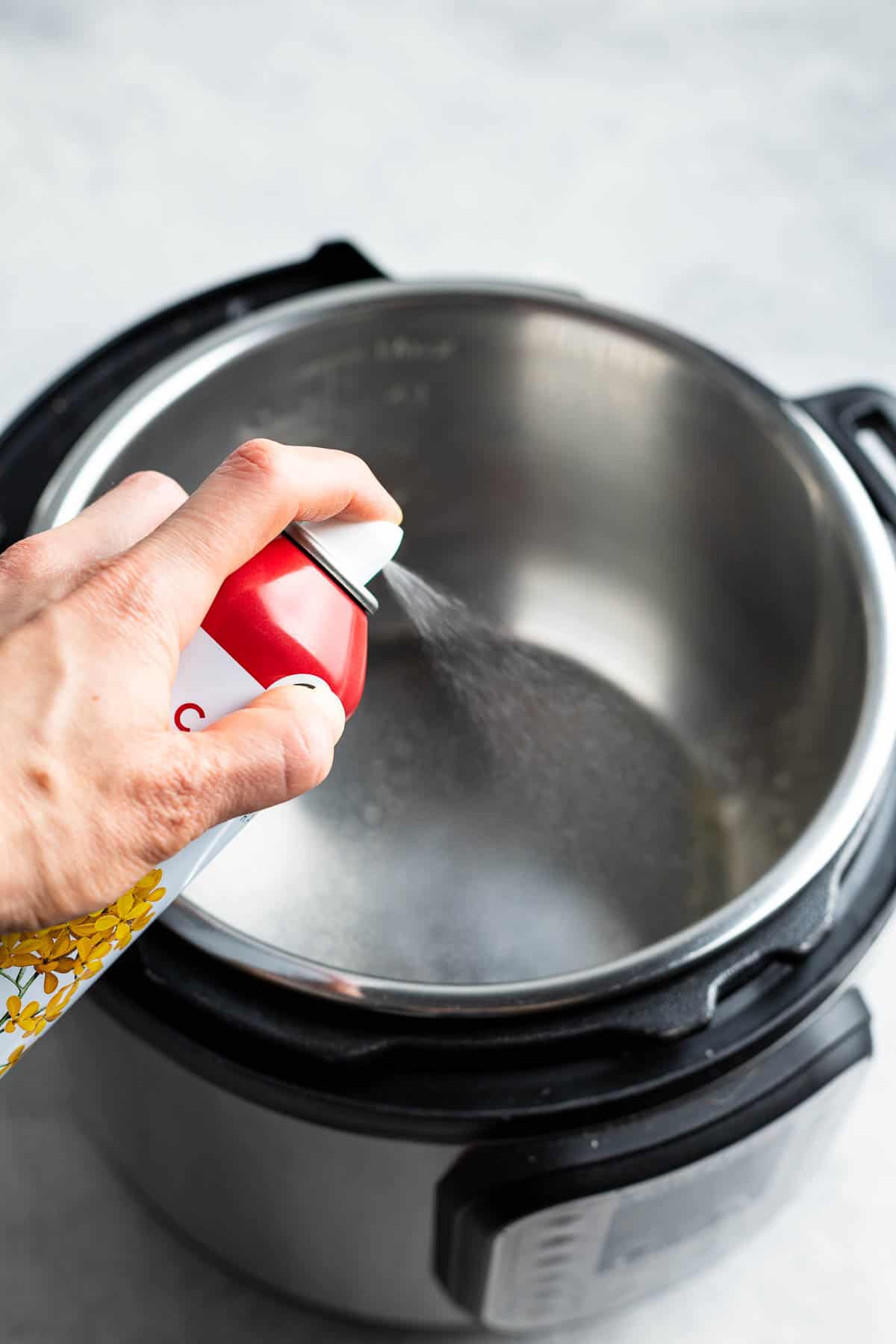 Spraying the Instant Pot insert with cooking spray.